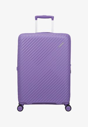 Valigia rigida viola con scanalature diagonali, quattro ruote girevoli, manico telescopico e logo American Tourister sulla parte anteriore.