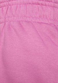 Ljust rosa tyg med en mjuk textur, med en samlad elastisk midja och släta sömmar utan synliga mönster eller hårdvara.