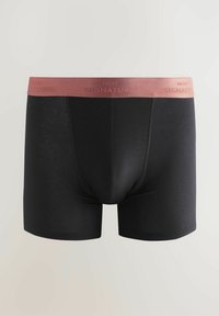 Schwarze Boxer Shorts mit einer glatten Textur und einem kontrastierenden elastischen Taillenbund in Pink, geprägt mit "NEXT SIGNATURE."