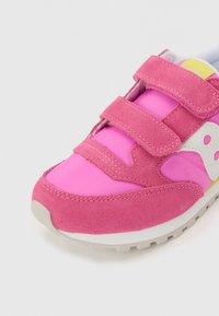 Chaussure de sport rose avec une combinaison de daim et de nylon, dotée de deux bandes Velcro et d'un accent de logo blanc sur le côté.