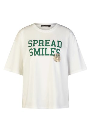 Weißes T-Shirt mit kurzen Ärmeln, grünem "SPREAD SMILES"-Schriftzug und einem kleinen dekorativen Patch mit goldenen und silbernen Verzierungen auf der Brust.