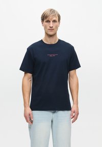 Ναυτικό μπλε βαμβακερό t-shirt με κοντά μανίκια, κλειστή λαιμόκοψη και εκτυπωμένο κείμενο "DENIM DESIGN STUDIO Since 2007" στο στήθος.