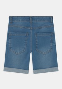 Jeansshorts, blåa med vikta fållar, som har två bakfickor och synlig söm. Slät textur, klassisk design.