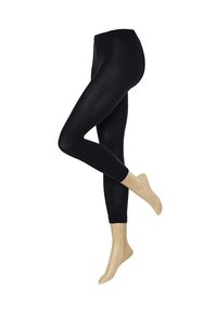 Schwarze Leggings mit glatter Textur und hohem Bund. Kombiniert mit hellbeigen gerippten Socken bis zum Knöchel.