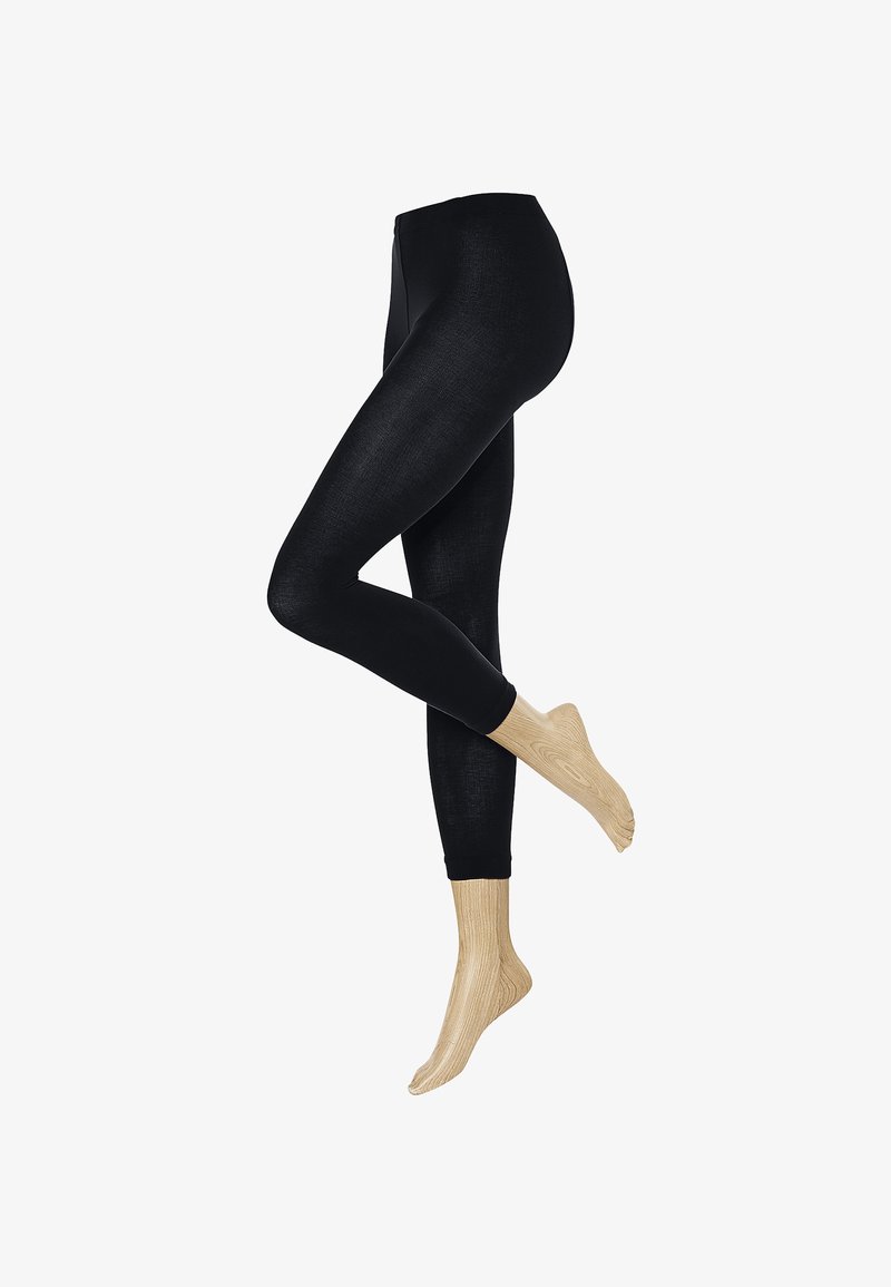 Schwarze Leggings mit glatter Textur und hohem Bund. Kombiniert mit hellbeigen gerippten Socken bis zum Knöchel.