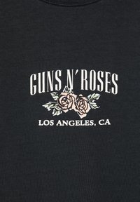 Tissu noir avec texte blanc indiquant Guns N' Roses et Los Angeles, CA, avec deux roses roses aux feuilles vertes entre les textes.