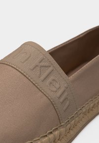 Μπεζ εσπαντρίγια με εύκαμπτη σόλα από πλεγμένο σχοινί και υφασμάτινο λουράκι με ανάγλυφο λογότυπο Calvin Klein.