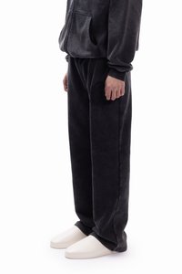 Ciemnoszara bluza polarowa z kapturem i przednią kieszenią, w zestawie z pasującymi spodniami polarowymi ozdobionymi haftowanym wzorem. Buty to minimalistyczne białe sneakersy.