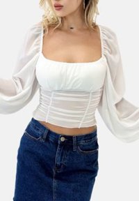 White cropped top with gathered bodice and sheer puff sleeves, paired with a high-waisted denim skirt. Smooth fabric; fitted design.