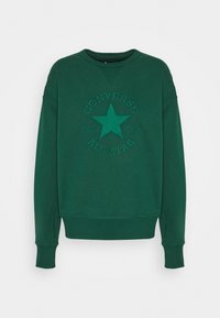 Felpa verde realizzata in morbido tessuto con un design a stella in rilievo e il testo "Converse Chuck Taylor All Star". Collo a giro e polsini a coste.