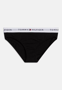 Culotte de bikini en coton noir avec une ceinture élastique blanche arborant le logo "TOMMY HILFIGER" et un petit emblème rouge. Texture lisse.