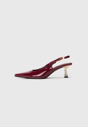 Γυαλιστερό μπορντό παπούτσι slingback με αιχμηρή μύτη και χρυσό toned πόρπη, με μεσαίο ύψος μεταλλικό τακούνι, σε λευκό φόντο.