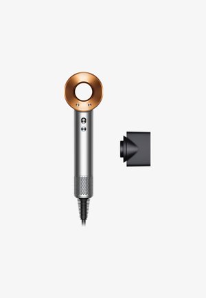 Haartrockner mit silbernem Gehäuse, einer kupferfarbenen runden Düse, zwei Tasten und einem strukturierten Fuß. Enthält ein schwarzes Zubehör mit einem konischen Design.