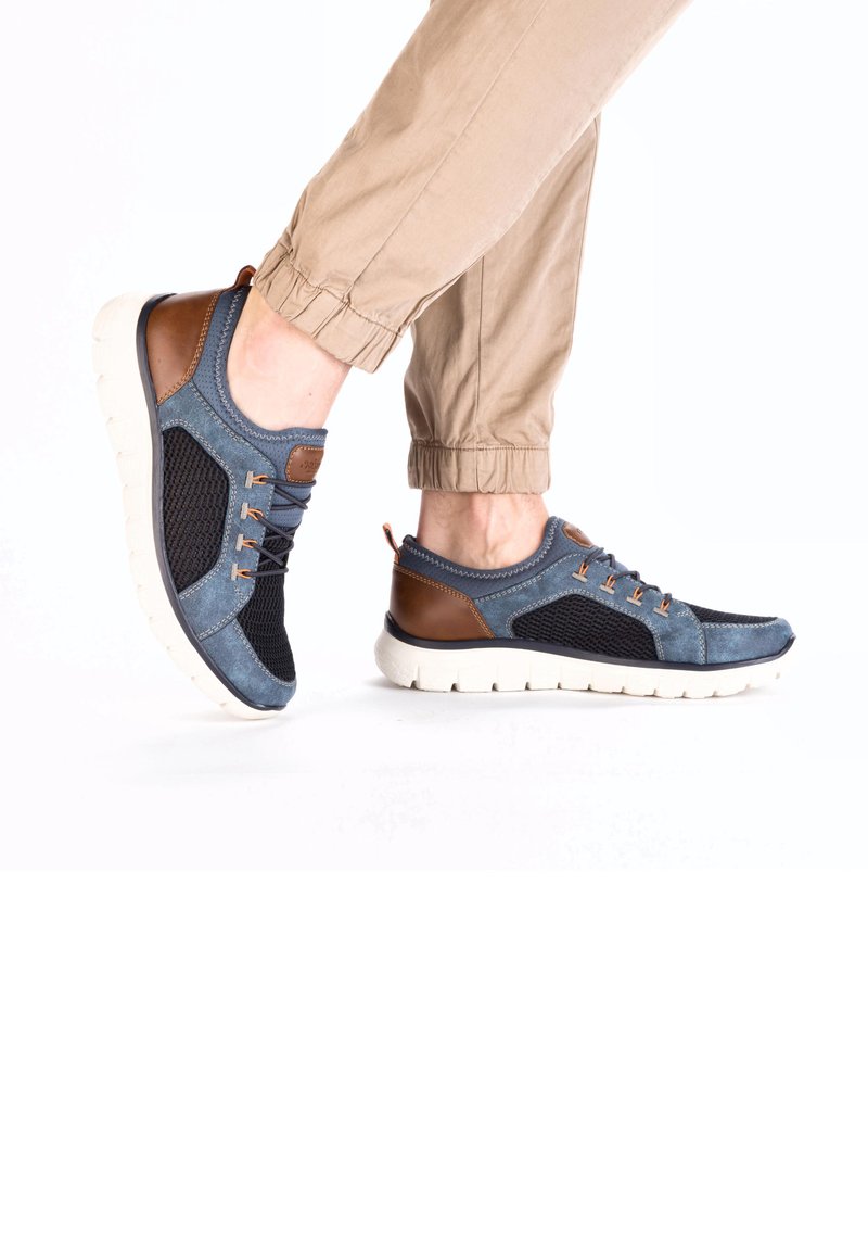 Baskets en mesh et nubuck bleu avec des accents en cuir brun, présentant des lacets beiges, une semelle blanche épaisse et un design sportif.