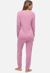 Camiseta de manga larga rosa y pantalones a juego, hechos de una tela suave. La camiseta presenta un escote amplio; los pantalones tienen puños ajustados en los tobillos.