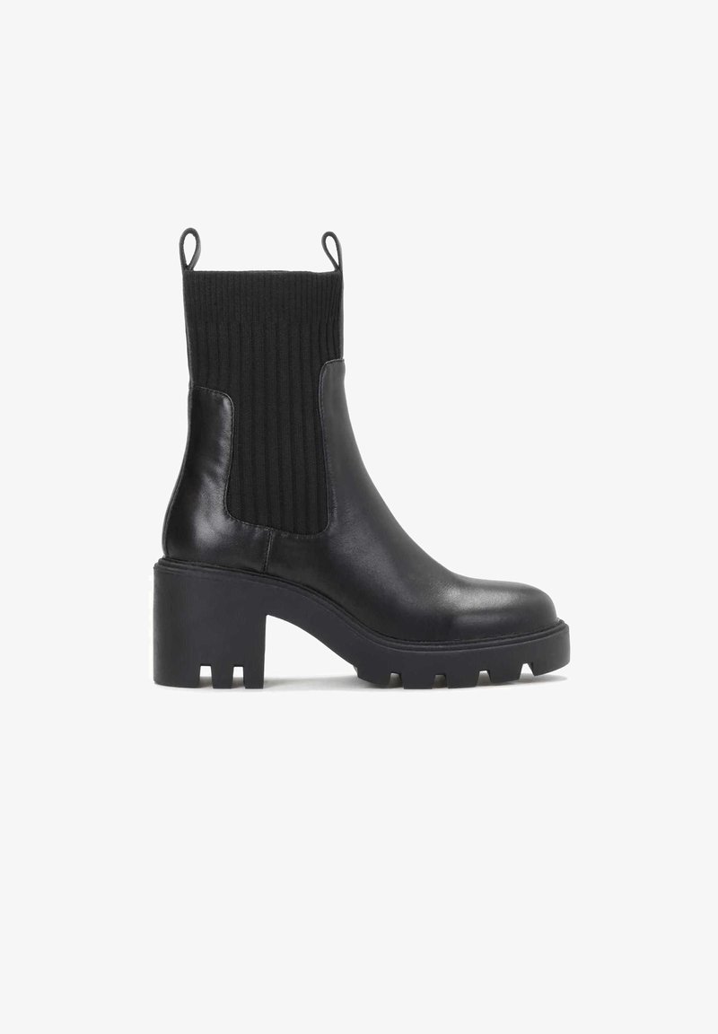 Botine din piele neagră cu un brâu din material texturat, toc gros și talpă texturată. Au știfturi pentru a fi ușor de purtat.