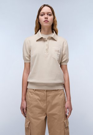 Beige polo t-shirt met korte mouwen, een geribbelde zoom, een sluiting met drie knopen en een patch pocket met een reliëf logo. Draagt over lichtbruine cargobroek.