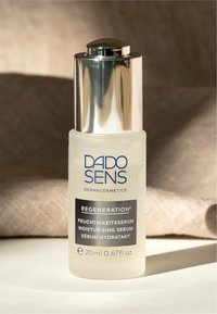 Durchsichtige Glasflasche mit frostierter Oberfläche, silberner Kappe, schwarzem Etikettentext. Enthält 20 ml Feuchtigkeitsserum, etikettiert in mehreren Sprachen.