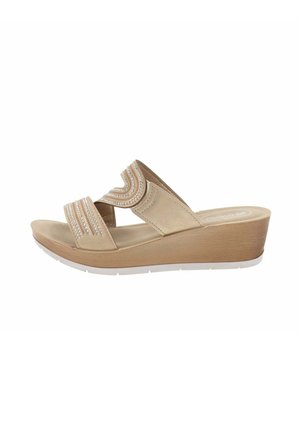 Sandales à talons compensés beiges avec deux brides croisées présentant un motif de vagues, ornées de petites perles en argent, reposant sur une semelle blanche.