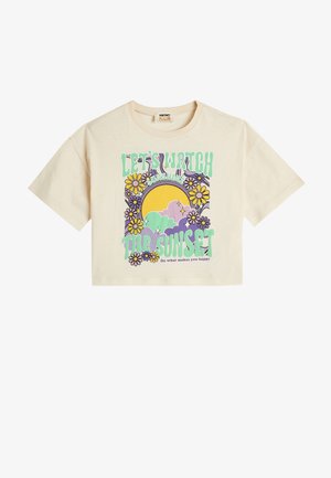 Beige cropped t-shirt med rund halsudskæring, prydet med et grafisk motiv af en solnedgang, skyer og blomster i lilla, gule og grønne nuancer.