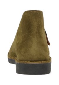 Stivale alla caviglia in suede verde oliva con texture liscia, tacco rotondo e suola in gomma nera a contrasto. Cuciture visibili sul retro.