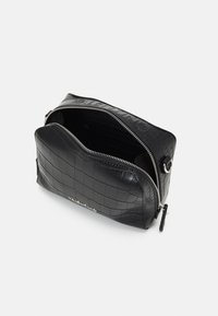 Black crocodile-embossed leather bag with a silver zipper, rounded shape, and exterior logo detailing. Open top reveals a spacious, lined interior.