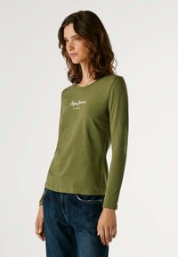 Olivgrünes Langarmshirt aus Baumwollmischung mit Rundhalsausschnitt, mit weißem Aufdruck "Pepe Jeans London" auf der Brust. Glatte Textur.
