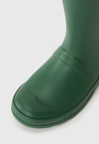 Grøn gummistøvle med en glat tekstur, rund tå og subtile sømdetaljer. Designet til vandmodstand og udendørs brug.