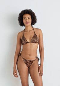 Bikini set s uzorkom leoparda, s trokutastim gornjim dijelom i dnom sa vezicama. Izrađen od teksturirane tkanine s smešnim i crnim uzorcima.