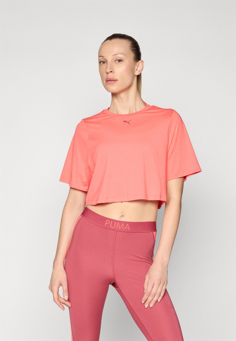 Korallfärgad cropped träningsskjorta med korta ärmar, med en liten logotyp. Matcha med högmidjade, bärfärgade leggings som visar varumärket.