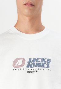Witte katoenen t-shirt met ronde halslijn, met het "JACK & JONES"-logo in blauwe en roze textured print, onder "INTERCONTINENTAL" en "core dept."