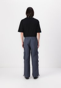 Black short-sleeve t-shirt paired with gray cargo pants featuring side pockets, elastic waistband, and adjustable hems. Simple and functional design.