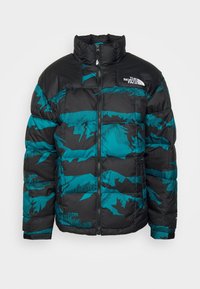 Giacca a vento con base nera e motivo camouflage turchese, dotata di un alto colletto, chiusura a zip e logo sul lato sinistro del petto.