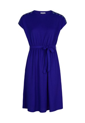 Paarse jurk tot de knie met korte mouwen, een ronde hals en een stoffen ceintuur. Heeft decoratieve stiksels op de schouders.