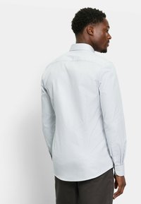 Hellblaues Hemd mit Muster, strukturiertem Kragen, langen Ärmeln und geknöpften Manschetten, mit glatter Stoffstruktur und tailliertem Schnitt.