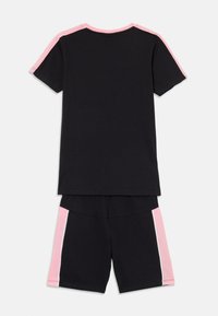 Sort bomulds T-shirt med lyserøde skulderdetaljer og matchende sorte shorts med lyserøde sideløsninger. Blød, afslappet design velegnet til leisure wear.