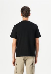 Sort bomulds T-shirt med korte ærmer og rund hals, vist fra bagsiden. Glat tekstur, standard pasform.