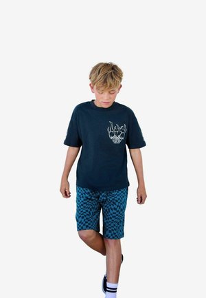 T-shirt en coton bleu marine avec impression graphique, associé à un short turquoise à motif à carreaux. Porté avec des chaussures noires et des chaussettes blanches.