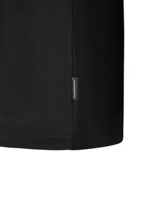 Black t-shirt with a smooth texture, featuring a side label with the brand name "Cleptomanicx." Short sleeves and a straight hemline.