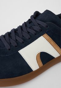 Jūrine nendrių sportbačiai su rudos ir kreminės spalvomis, suapvalintais raišteliais, tekstūruotu paviršiumi ir guminiais padais.