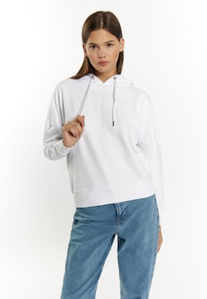 Witte hoodie met een relaxte pasvorm, geribbelde manchetten en een kangoeroezak. Gekleed met lichtblauwe denimjeans.