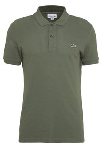 Polo vert olive en coton texturé, avec un col classique, une patte de boutonnage à deux boutons et un petit logo brodé sur la poitrine.