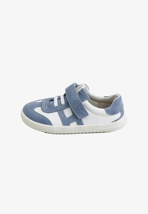 Zapatilla infantil de cuero blanco con detalles en ante azul, con tira de velcro y cordones elásticos blancos sobre una suela de goma blanca.