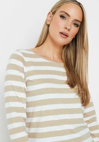 Langsleeve top in beige en witte horizontale strepen, met een ronde halslijn en een zachte, gestructureerde stof.