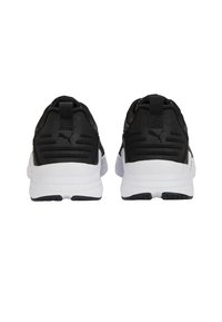 Černobílé tenisky Puma viděné ze zadní strany, ukazující poutka na patě a texturované podrážky.