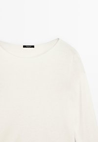 Kremowy sweter z szerokim dekoltem i długimi rękawami, z czarną metką z napisem "Massimo Dutti" w pobliżu kołnierza.