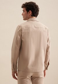 Beige knapjakke, bomuldsblanding, med en afslappet pasform, skjortekrave, lange ærmer og knapmanchetter. Glat tekstur, enkelt design.