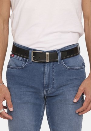Schwarzer Ledergürtel mit strukturiertem Finish, ausgestattet mit einer silbernen Schnalle und kontrastierenden Nähten, getragen über blauen Jeans.