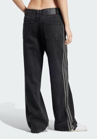Schwarze, weite Jeans mit hoher Taille, elastischem Bund, zwei Gesäßtaschen und kontrastierenden seitlichen Streifen in einer hellen Farbe.