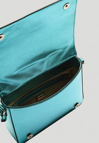 Borsa a tracolla turchese con finitura metallica, dotata di chiusura a pattina, tasca interna e dettagli in metallo argentato.